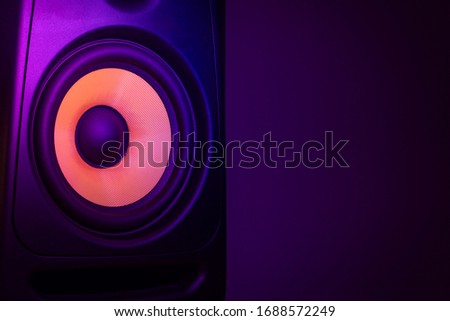 Music studio speaker, with a yellow membrane, isolated on a dark purple background, with space for text on the right side. Electronic music concept.