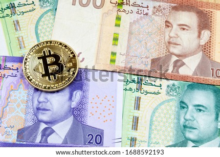 Close-up on a golden Bitcoin coin on top of a stack of Moroccan dirham banknotes.
