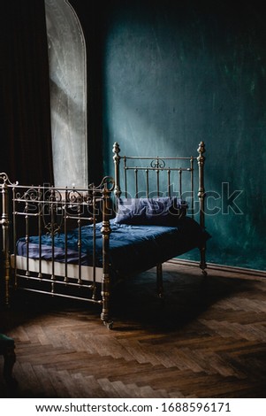Vintage bed in dark blue empty bedroom. Vertical photo.