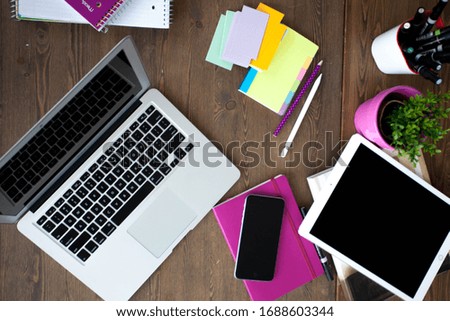 Office desk with laptop, tablet and phone. Yellow sheets for writing, pencils and a flower in a pot on the table. Office Worker Desk