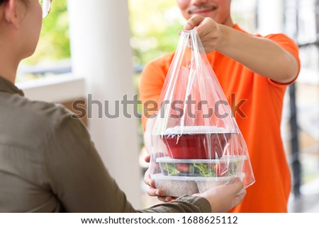 Delivery man giving lunch box meal in the bag to cutomer that ordered online at home Royalty-Free Stock Photo #1688625112