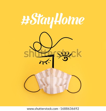 Corona virus awareness concept of a fabric antivirus face mask with an illustration, Stay Home hashtag typography on yellow background Royalty-Free Stock Photo #1688636692