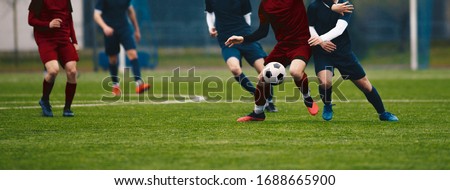 Horizontal picture of soccer match. Soccer football players competing for ball and kick ball during match in the stadium. Footballers in action on soccer league game. Senior level sport competition
