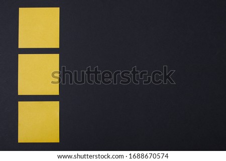 A set of yellow colored paper sticky notes on black background with space. 