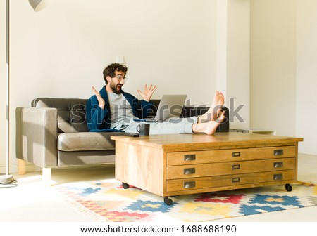 young cool man sitting on a sofa at living room watching tv