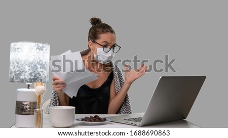 Woman in medical mask and glasses working hard from home during sick leave