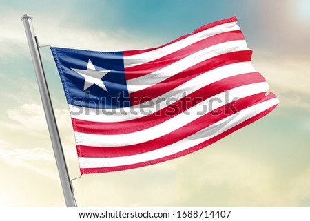 Liberia national flag cloth fabric waving on the sky with beautiful sun light - Image