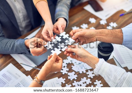 Group of business workers with hands together connecting pieces of puzzle at the office Royalty-Free Stock Photo #1688723647