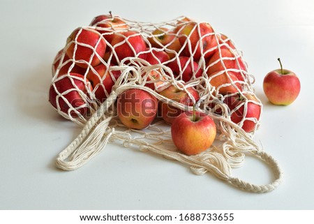 Mesh textile bag full of red apples. .Zero waste food shopping. Eco natural bags on white background. Eco friendly concept.Plastic free minimalist life style.Reuse, reduce, recycle. Say no to plastic