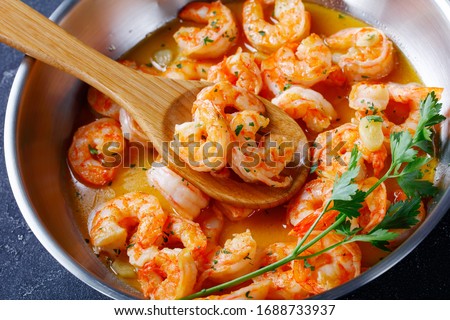 Keto diet dish shrimp scampi with garlic and butter sauce sprinkled with parsley, on a skillet on concrete background, horizontal orientation, close-up Royalty-Free Stock Photo #1688733937
