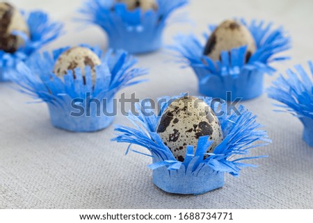 Pattern of decorated quail eggs in the form of blue flowers on a background of natural linen fabric. Children's creativity, crafts for Easte. Close up