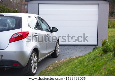 Free-standing garage in the garden with a car parked in front of the gate Royalty-Free Stock Photo #1688738035