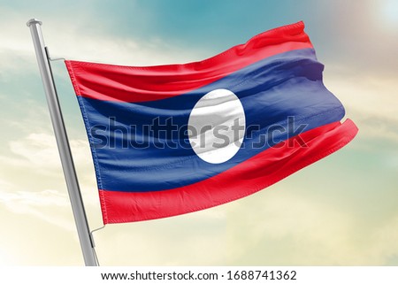 Laos national flag cloth fabric waving on the sky with beautiful sun light - Image