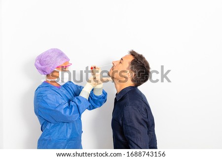 A doctor in a protective suit taking a nasal swab from a person to test for possible coronavirus infection Royalty-Free Stock Photo #1688743156