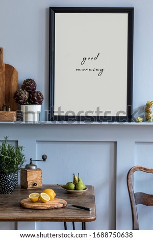 Interior design of kitchen space with black mock up photo frame, wooden table, chairs, herbs, cutting board, food and kitchen accessories in modern home decor.