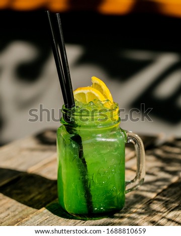 Sunny picture with fresh green lemon citrus lemonade with ice in maison jar on wooden table