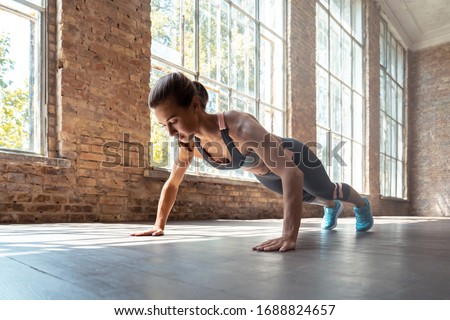 Young fit sporty active woman wear sportswear standing in plank pose doing yoga fitness training workout stretching core push up pushup exercise on wooden floor in modern sunny gym space indoors. Royalty-Free Stock Photo #1688824657