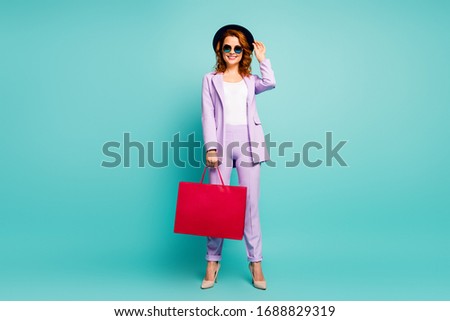 Full body photo of charming positive worker tourist work trip hold shopping bags wear violet pants trousers high-heels jacket hat formalwear headwear isolated over teal turquoise color background