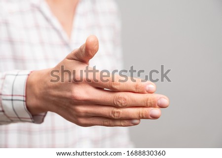 Female hand showing a greeting sign for a handshake on a neutral background
