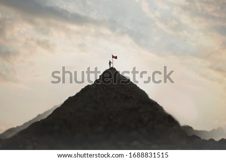woman plants his flag on the mountain peak as a sign of success Royalty-Free Stock Photo #1688831515