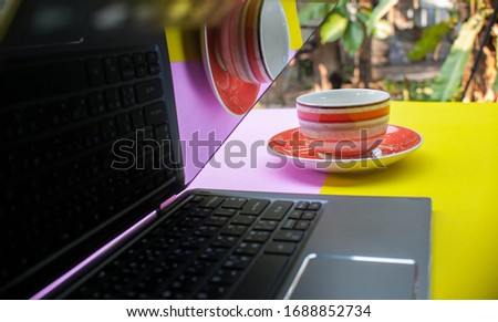 
White blank coffee cups that place on orange plates and notebook computers. Glasses arranged against contrasting background colors look comfortable on the desk