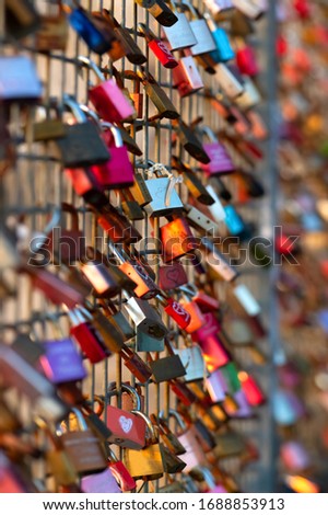 Colorful Love locks on a fence in warm evening sun in Germany as symbol for everlasting love and the promise to stay together backlight by sunset