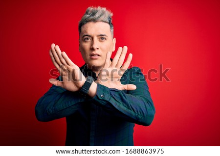 Young handsome modern man wearing elegant green shirt over red isolated background Rejection expression crossing arms doing negative sign, angry face