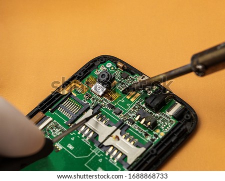 Repairing a mobile phone with a soldering iron and screwdriver