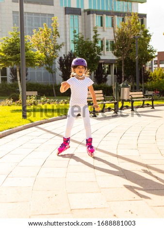 Little girl on roller skates in helmet at park