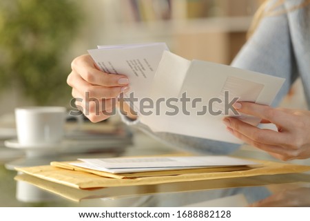 Close up of girl hands opening an envelope with a letter inside on a desk at home Royalty-Free Stock Photo #1688882128