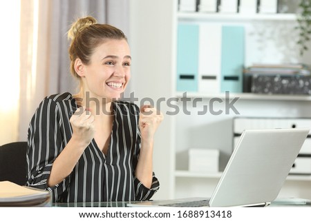 Excited entrepreneur celebrating good news on laptop stting on a desk in the office Royalty-Free Stock Photo #1688913418