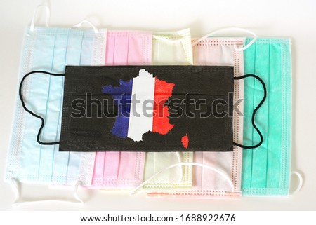 Black medical mask with picture of French Flag in Map Shape. Black medical mask is a symbol of mortal danger of coronavirus in France. Close-up protective masks textile filter.