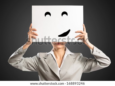 business woman holding a poster with a painted face on it instead of a face, the concept of duplicity in business
