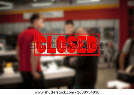 the inscription "closed" on the background of an electronics supermarket / equipment store. The supermarket is closed. Supermarket quarantined due to coronavirus. Blur store photo.