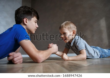 The brothers are engaged in arm wrestling. Two quarantined boys in self-isolation enjoy communication. Insulation in your home. Close-up of hands and games.