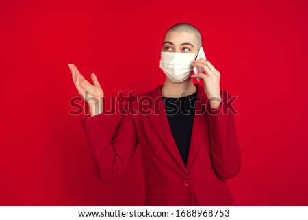 Talking on phone. Portrait of young caucasian bald woman isolated on red studio background. Beautiful female model in gloves, face mask. Human emotions, facial expression, sales, ad concept.