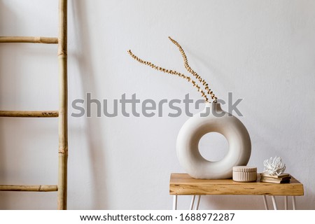Interior design of living room with stylish dried flowers in vase, wooden ladder and personal accessories in modern home decor. 