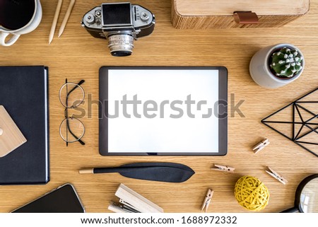 Stylish flat lay business composition on the wooden desk with mock up tablet screen, cacti, notes, photo camera and office supplies in modern concept.
