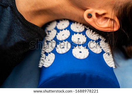 Caucasian female on acupressure mat in home self acupuncture massage. Close-up of white woman neck on a blue pillow with thin needles. Chinese traditional medicine. Royalty-Free Stock Photo #1688978221