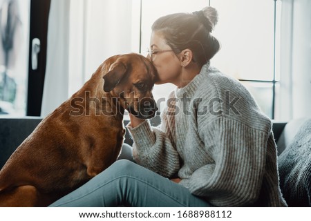 Woman cuddles, plays with her dog at home because of the corona virus pandemic covid-19 Royalty-Free Stock Photo #1688988112
