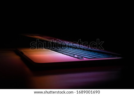 laptop half closed from the side in the dark