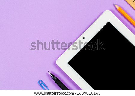 Various stationery and tablet with a phone for work and study and a cup of coffee on a purple background
