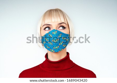 Pensive,  thoughtful woman wearing protection handmade face mask during the quarantine of coronavirus infection outbreak. Copy, empty space for text Royalty-Free Stock Photo #1689043420