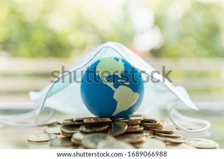 Global Money, Business, Healthcare in Cornavirus (COVID-19) Situation Concept. Mini world ball on pile of gold coins under surgical face mask with copy space. Royalty-Free Stock Photo #1689066988