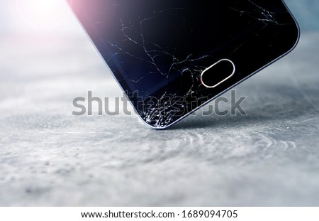 Cracked smartphone screen. The smartphone falls  to the floor and the screen crashes. Moment of fall. 