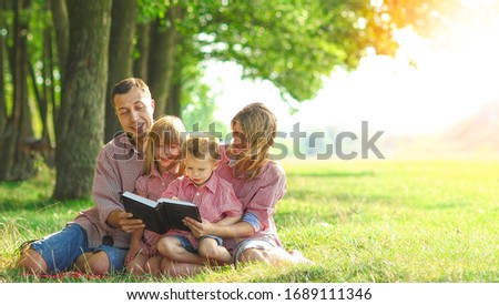 happy young family reading the Bible in nature Royalty-Free Stock Photo #1689111346