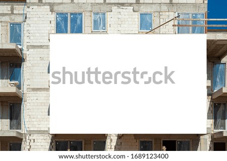 Blank white advertising banner on the facade of residential building under construction