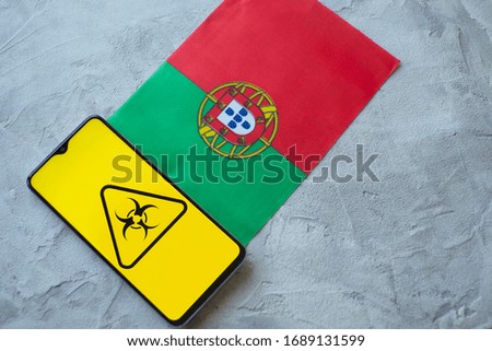 Epidemiological situation in the country Portugal. Flag and smartphone with news and a biohazard symbol. The pandemic virus, concept