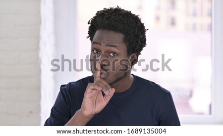 Portrait of Young African American Man Putting Finger on Lips