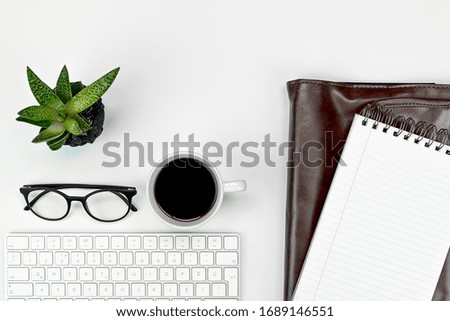 White office table, computer keyboard, glasses, cup of coffee and office supplies. Top view with copy space, flat lay